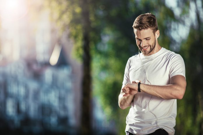 Delighted athlete checking fitness tracker outdoors