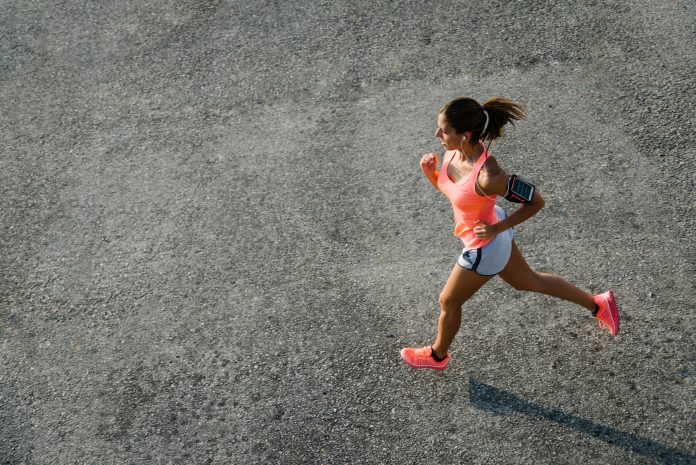 Top view of sporty young fit woman running on urban asphalt. Female athlete training outside in summer. peeing when running